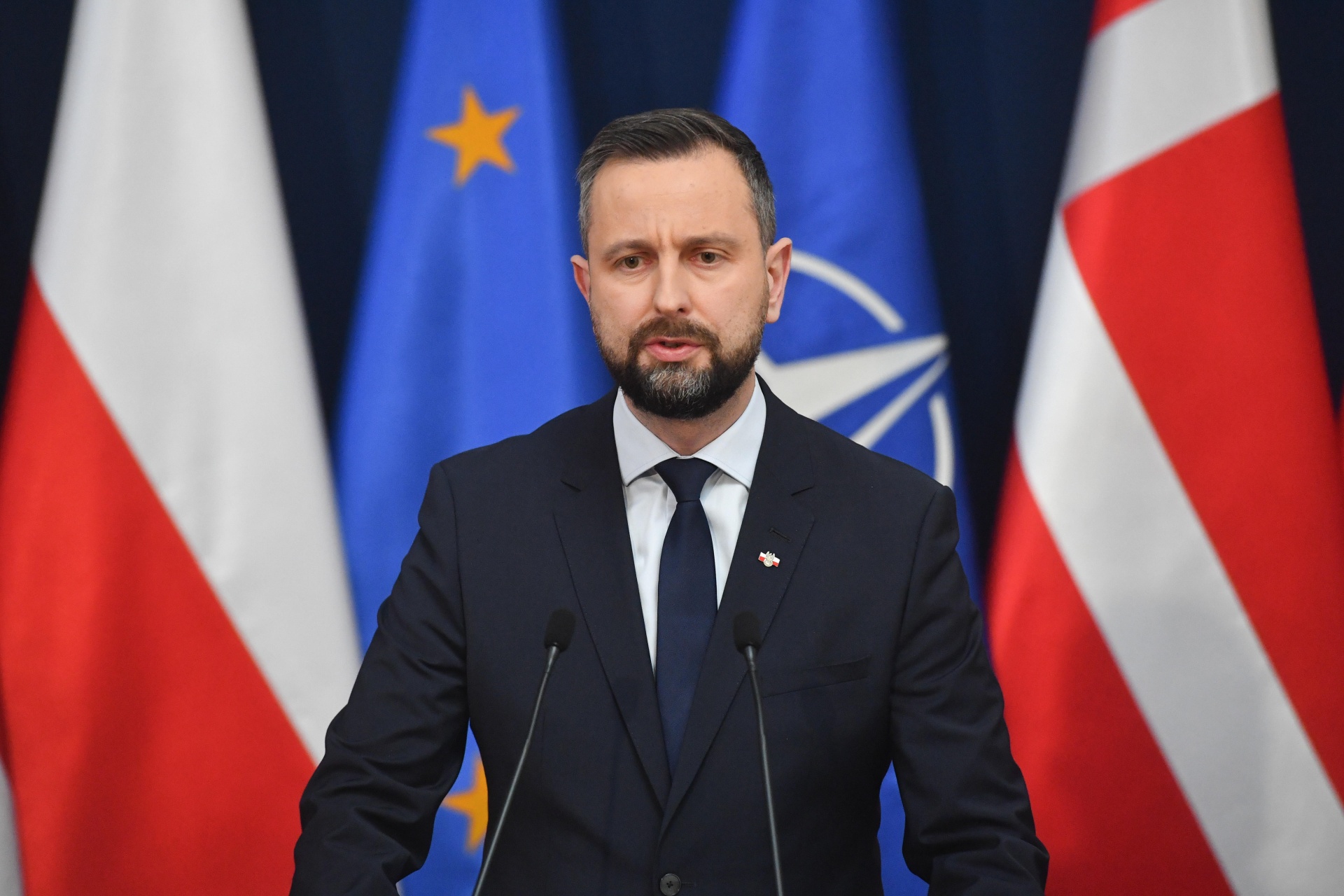 Władysław Kosiniak-Kamysz na tle flagi Polski oraz sztandaru NATO
