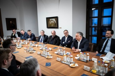 Premier Węgier, jego urzędnicy oraz zagraniczni dziennikarze siedzą przy dużym stole konferencyjnym