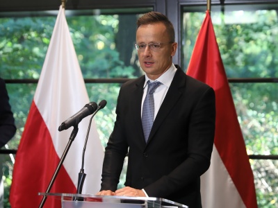 Szef węgierskiej dyplomacji Peter Szijjártó na tle polskich flag