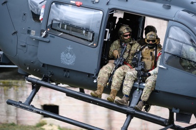 Żołnierze w mundurach siedzą przy otwartych drzwiach lecącego śmigłowca