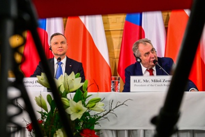 Prezydenci Polski i Czech siedzą na tle flag narodowych