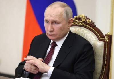 Zbrodniarz Władimir Putin siedzi na tle rosyjskiej flagi