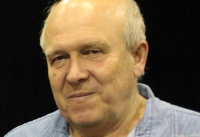 Portret Lajosa Pálfalviego na czarnym tle. Tłumacz ubrany jest w niebieską koszulę i lekko się uśmiecha.